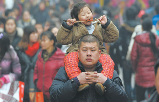 合肥淮河路步行街,一个小朋友骑在家长肩上享